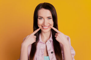 Woman pointing to smile on orange background