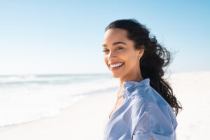 Woman standing on beach smiling into camera