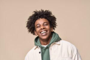 Happy joyful young man smiling on beige background