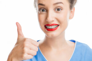 Close up portrait of a woman with tooth braces on the white background. Woman worried about a new smile with braces