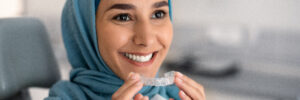 Woman wearing hijab holding clear aligners