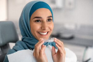 Woman wearing hijab holding clear aligners