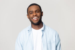 Head shot portrait happy African American man with wide healthy smile, satisfied client customer looking at camera, handsome young male feeling positive, isolated on grey background